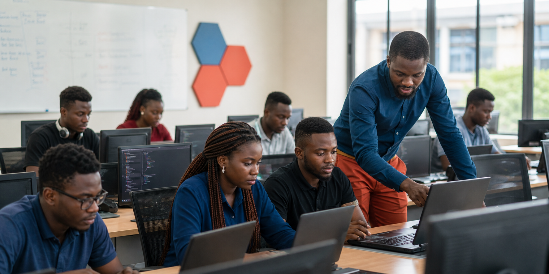 African software engineering students learning in a modern IT classroom with laptops and code on screens